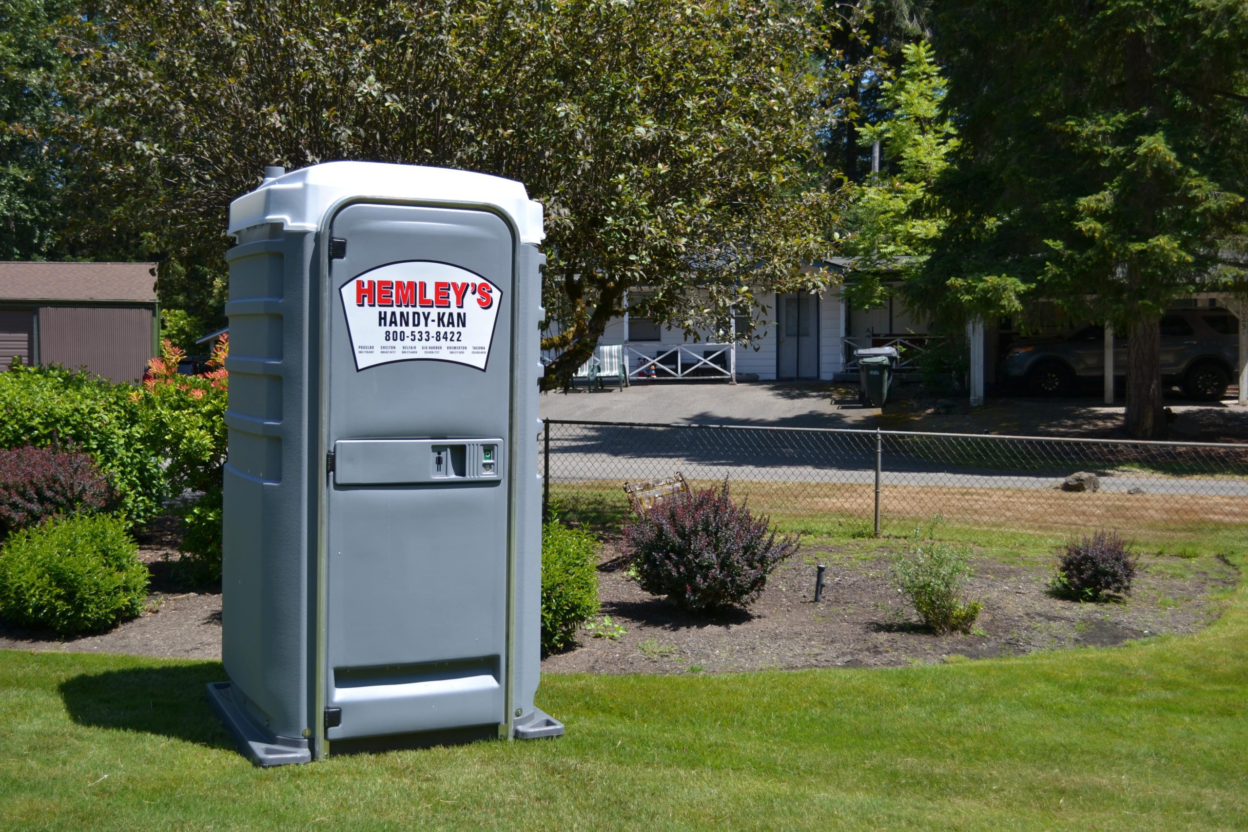 Gray Portable Toilet Rental in a Yard